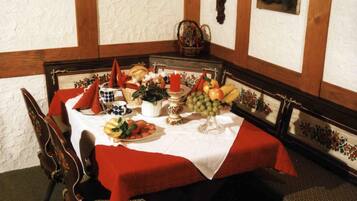 A dining table set with a white tablecloth, red napkins, and various fruits and vegetables.