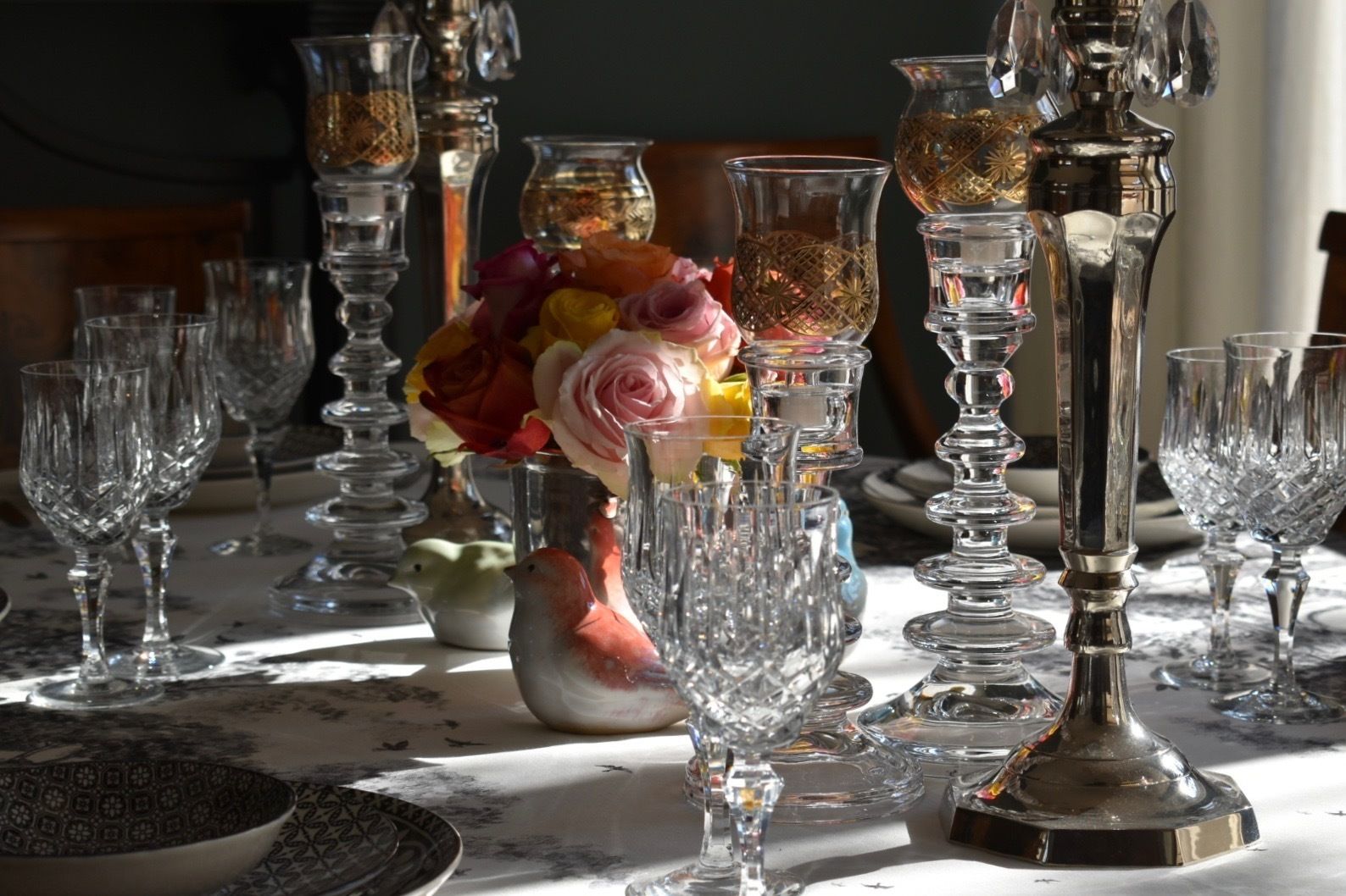 A table set with various glassware and a vase of flowers.