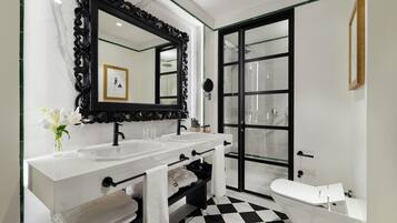 Une salle de bain avec deux lavabos, un grand miroir, des toilettes et une douche à parois de verre.