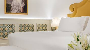 Habitación de hotel con cama, mesita de noche, lámpara, cuadro enmarcado y baldosas con diseño en las paredes.