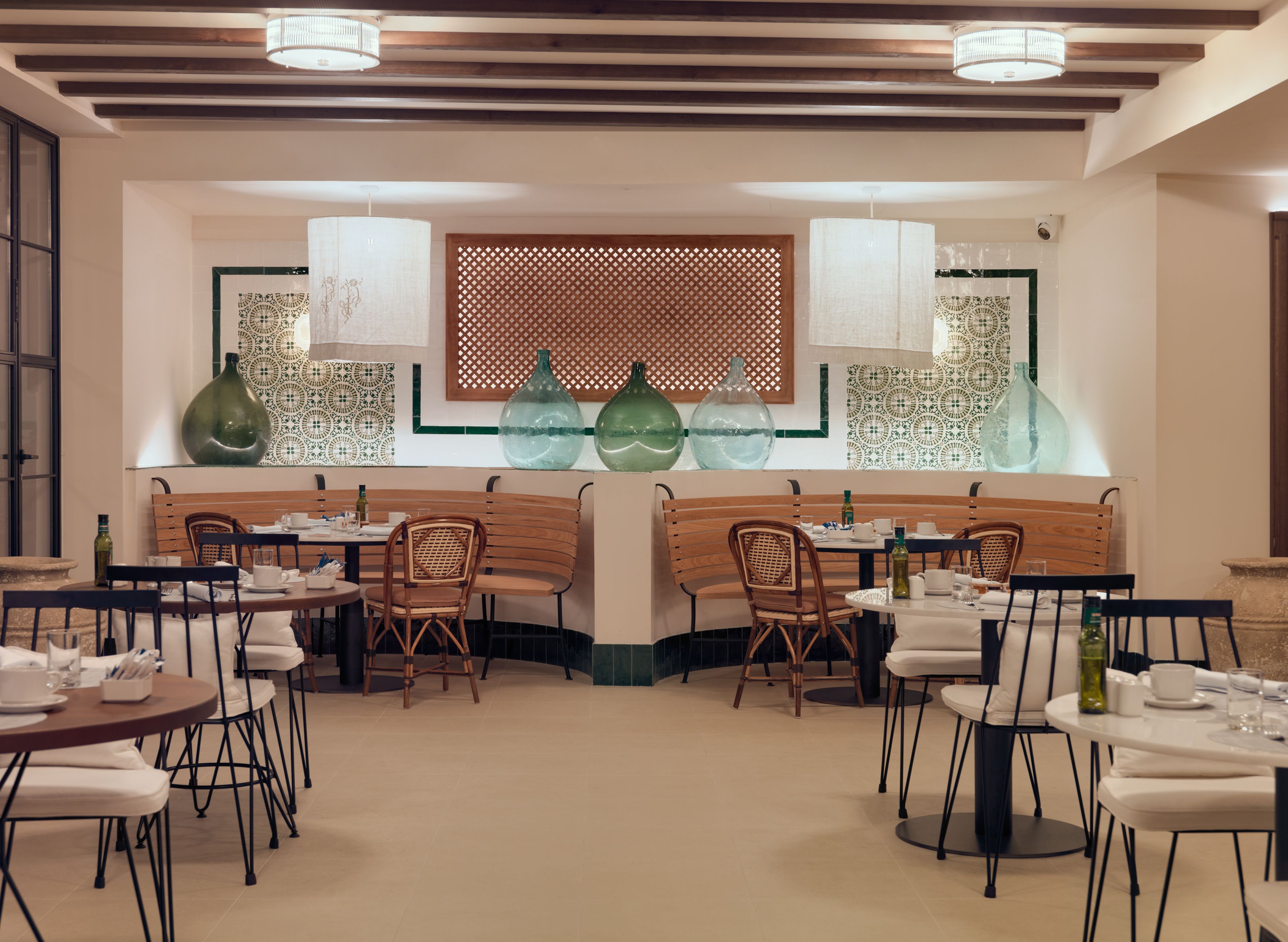 A restaurant interior with wooden booths, round tables, and hanging pendant lights.