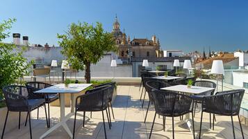 Un patio al aire libre con mesas y sillas, con vista a un edificio histórico con cúpulas y agujas.