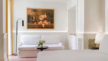 Un dormitorio moderno con un sofá blanco, una cama, un cuadro de frutas y una lámpara de pie.