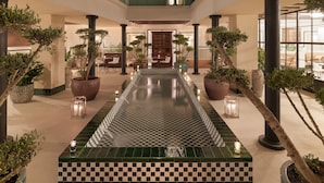 A spacious indoor area with a central checkered floor, potted plants, and a seating area with tables and chairs. - H10 Casa de la Plata (Seville)