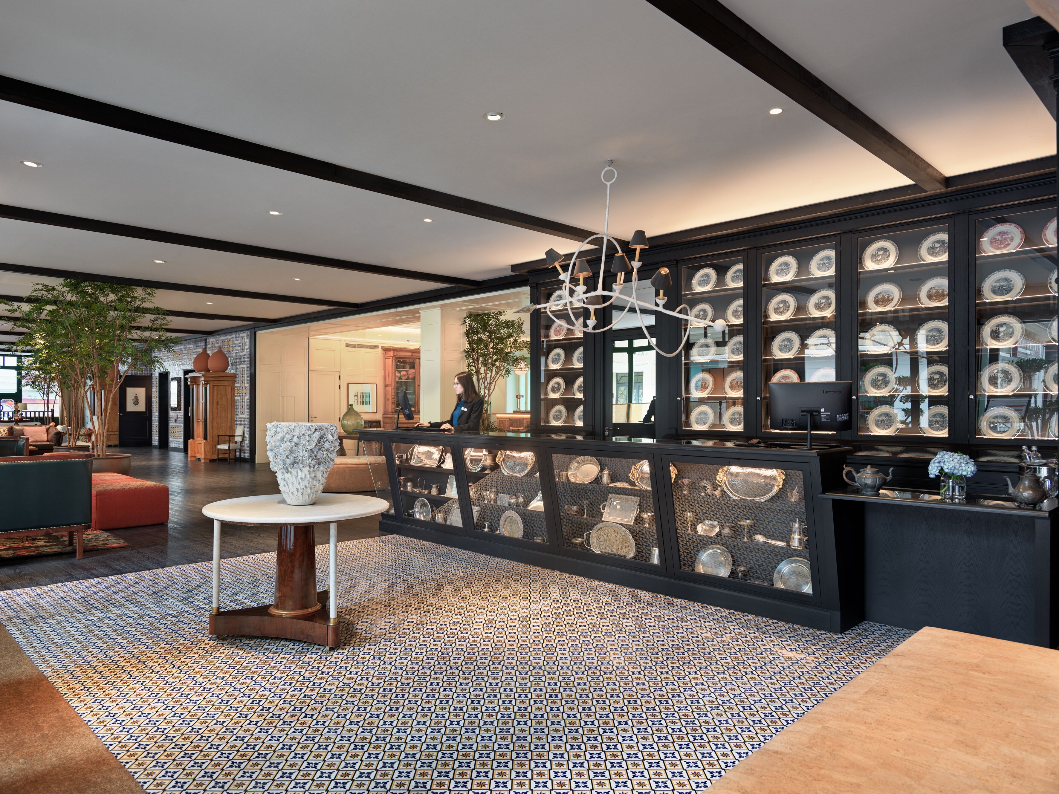 Un interior moderno con piso estampado, una mesa central y una exhibición de platos en la pared.
