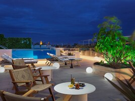 Una piscina al aire libre, sombrillas, sillones reclinables de piscina