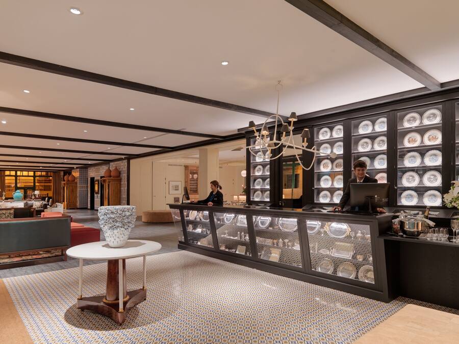 A lobby with a reception desk, a chandelier, and a wall of decorative plates.