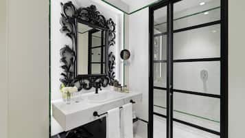 A modern bathroom with a large mirror, white vanity, black sink, and a glass shower enclosure.