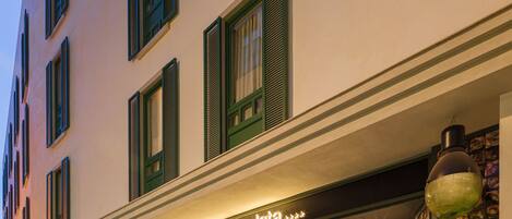 A hotel facade with multiple windows, a sign reading "Hotel Casa de la Playa," and outdoor potted plants.