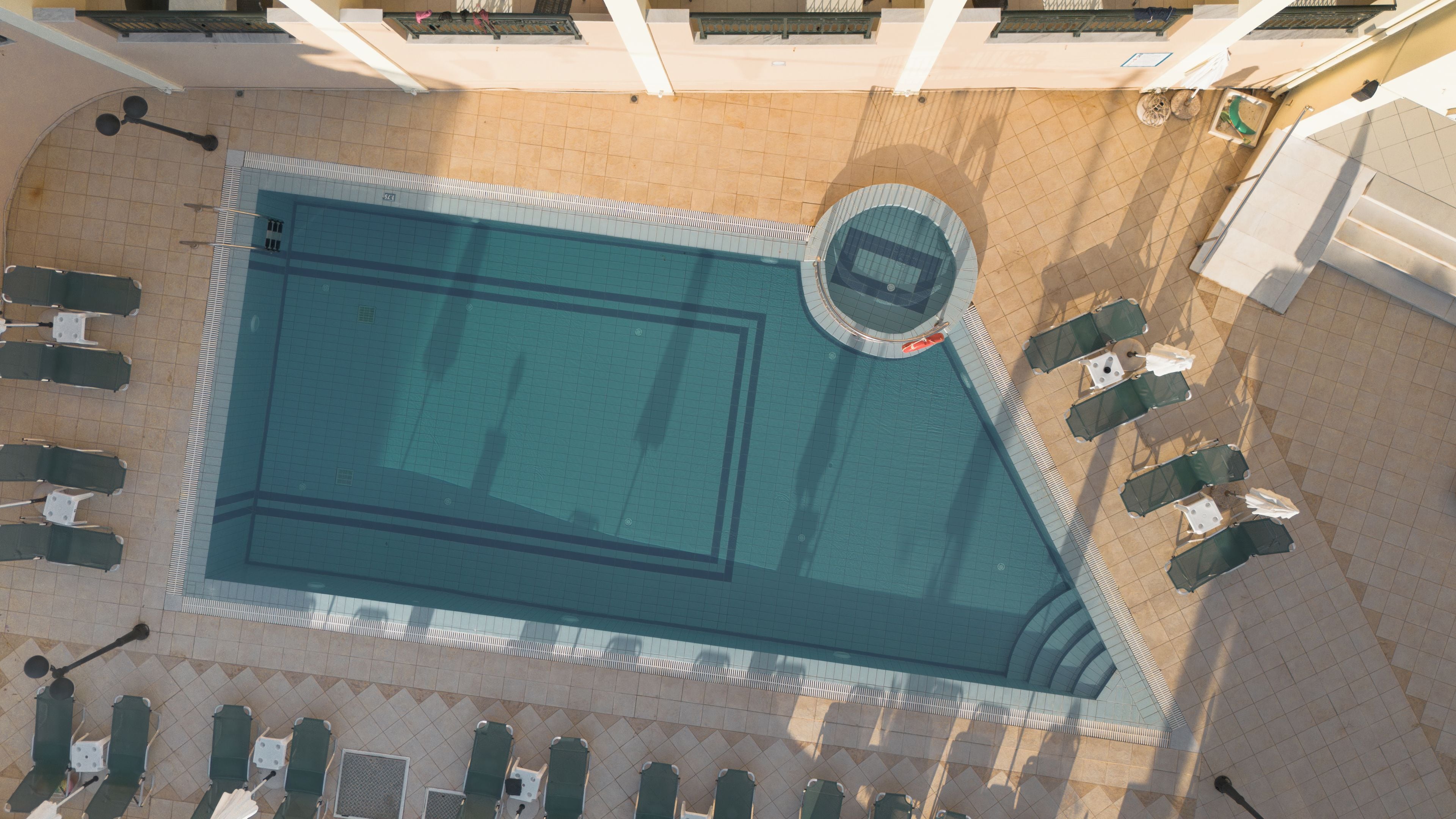 An aerial view of a swimming pool with sun loungers and a lifeguard stand.