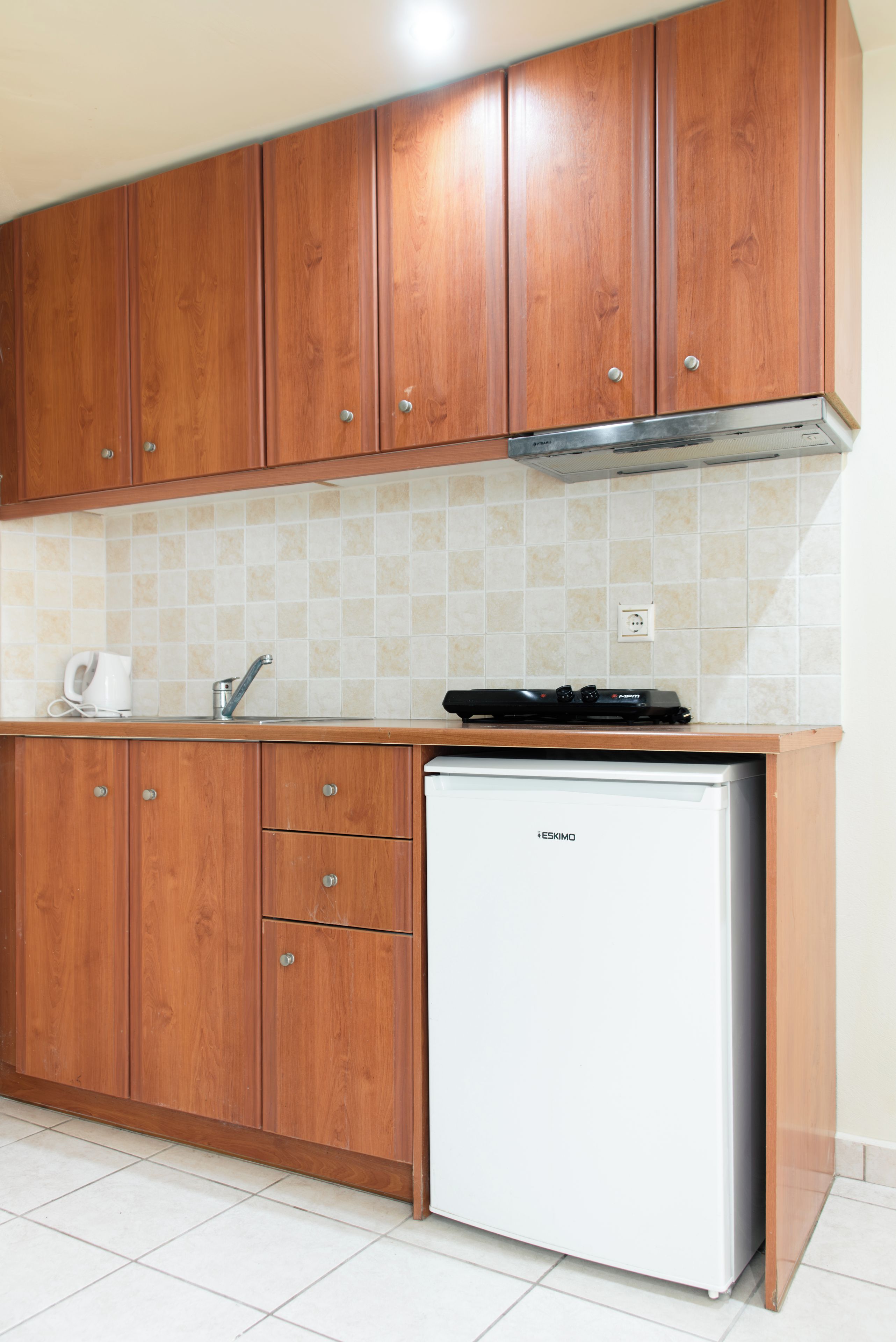 Una cocina con armarios de madera, un refrigerador blanco y salpicadero de azulejos.