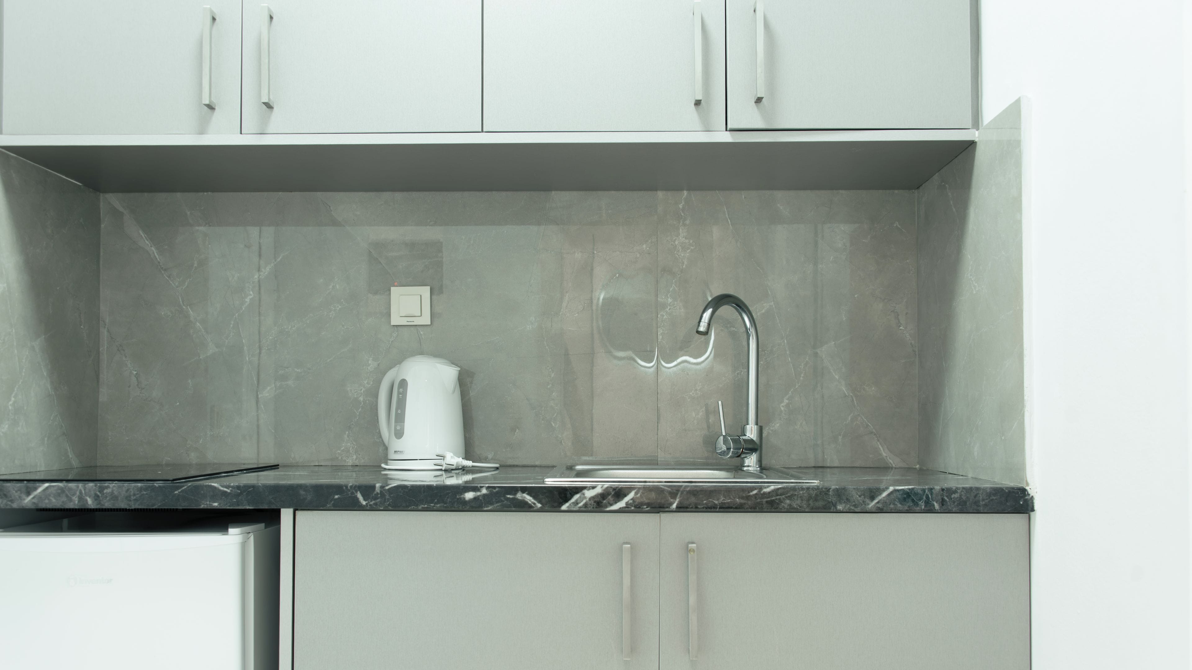 Una cucina dal design moderno, con un piano di lavoro in marmo, un lavello incassato e un bollitore.