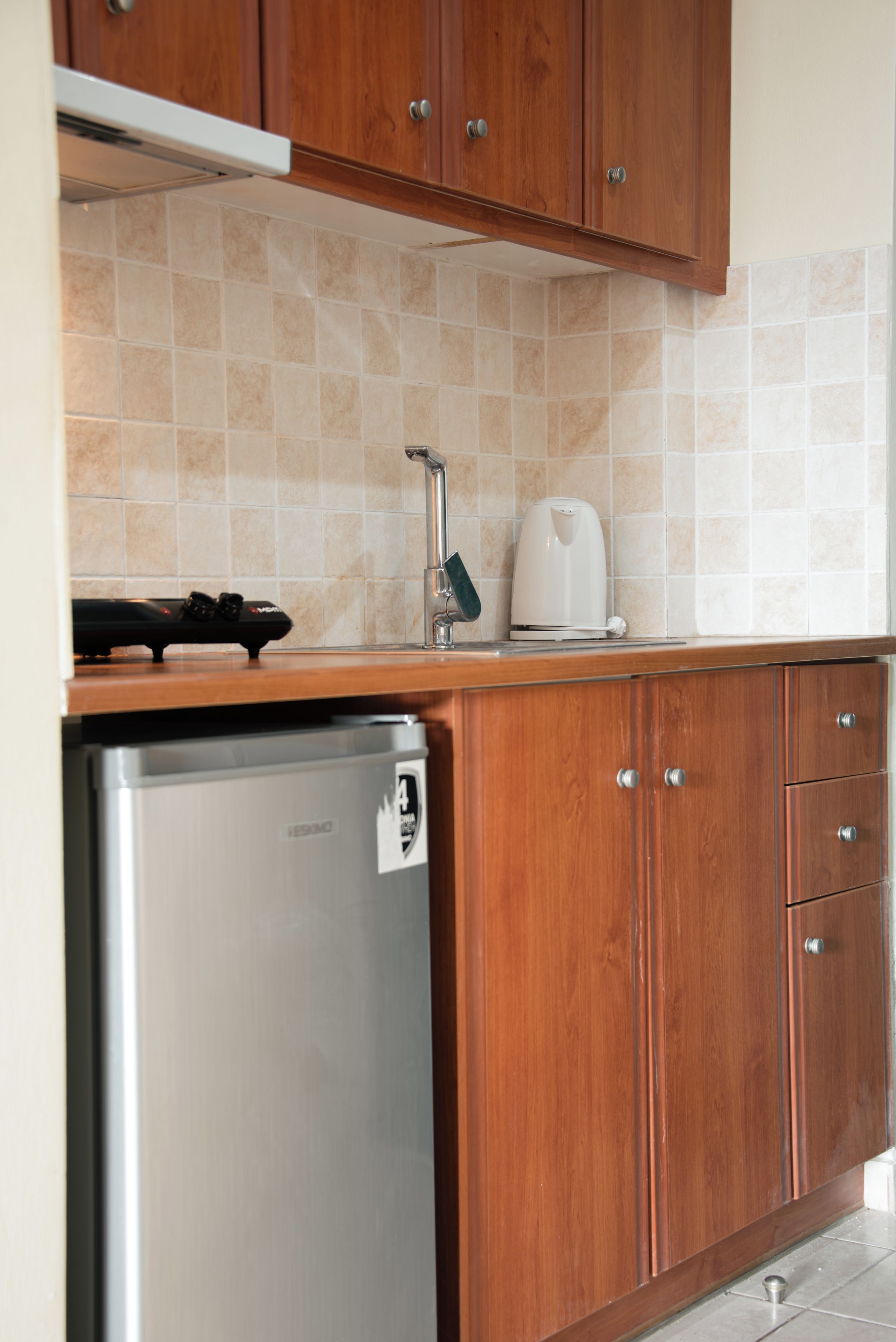 Una cucina con mobili in legno, un frigorifero in acciaio inossidabile e uno schienale piastrellato.