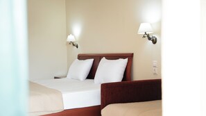 A hotel room with a bed, two bedside lamps, and a wooden headboard. - Timos Hotel (Zakynthos)