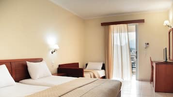 A hotel room with a bed, a desk, a chair, and a window with curtains.