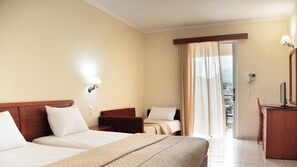 A hotel room with a bed, a desk, a chair, and a window with curtains. - Timos Hotel (Zakynthos)