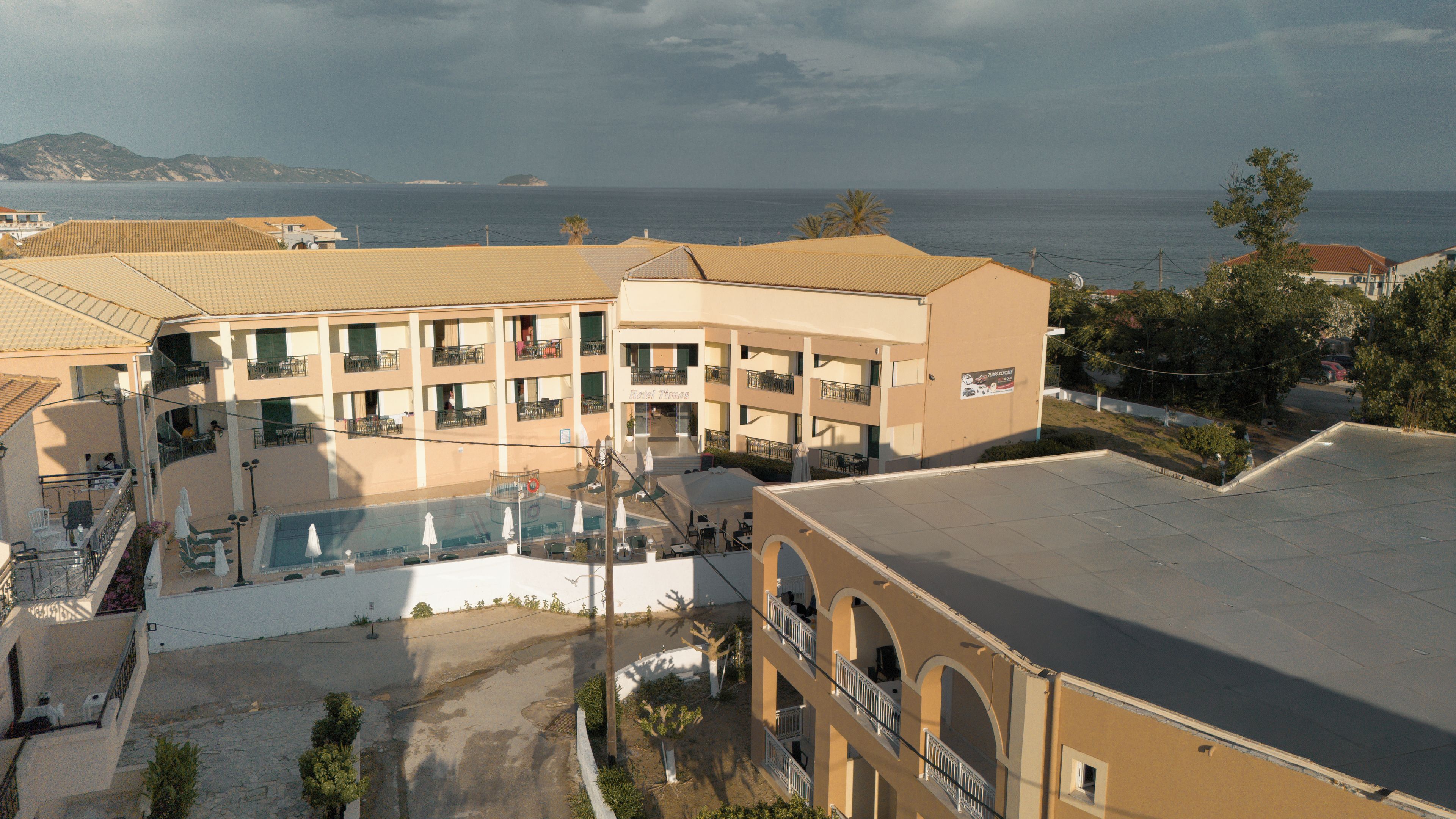 A hotel with multiple balconies, a swimming pool, and a view of the sea.