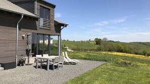 Una casa moderna con un patio, una mesa de comedor y asientos exteriores.