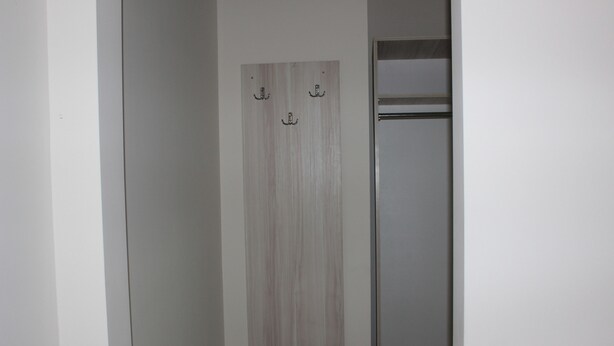 Um corredor estreito com porta de madeira e um suporte de metal.