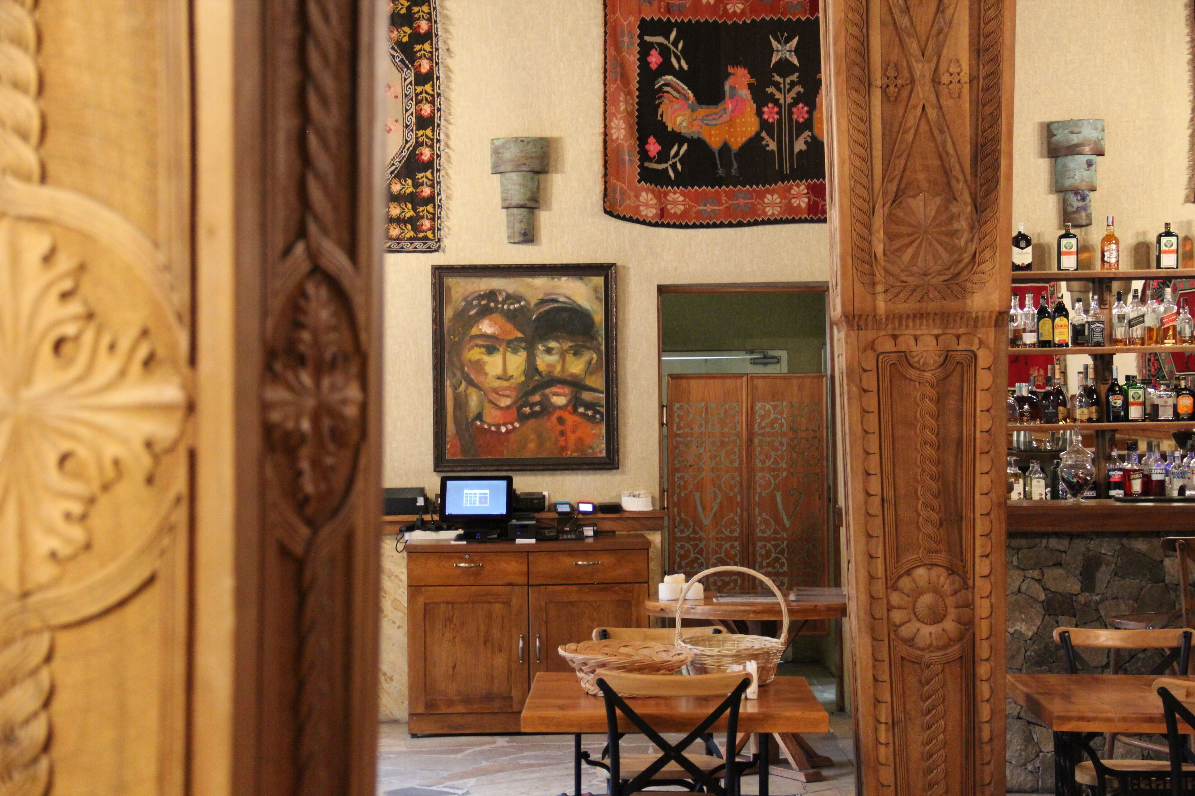 Una zona de bar con mobiliario de madera, una computadora y una pared decorada con adornos.