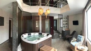 Un interior moderno con un jacuzzi, zona de estar y una escalera que conduce a otro nivel.
