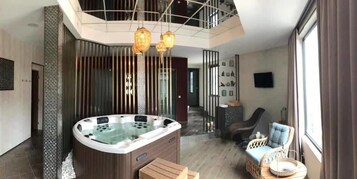 Un interior moderno con un jacuzzi, zona de estar y una escalera que conduce a otro nivel.
