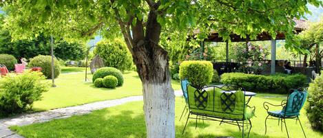 Un jardín con un árbol, un sendero de piedra y mobiliario exterior.