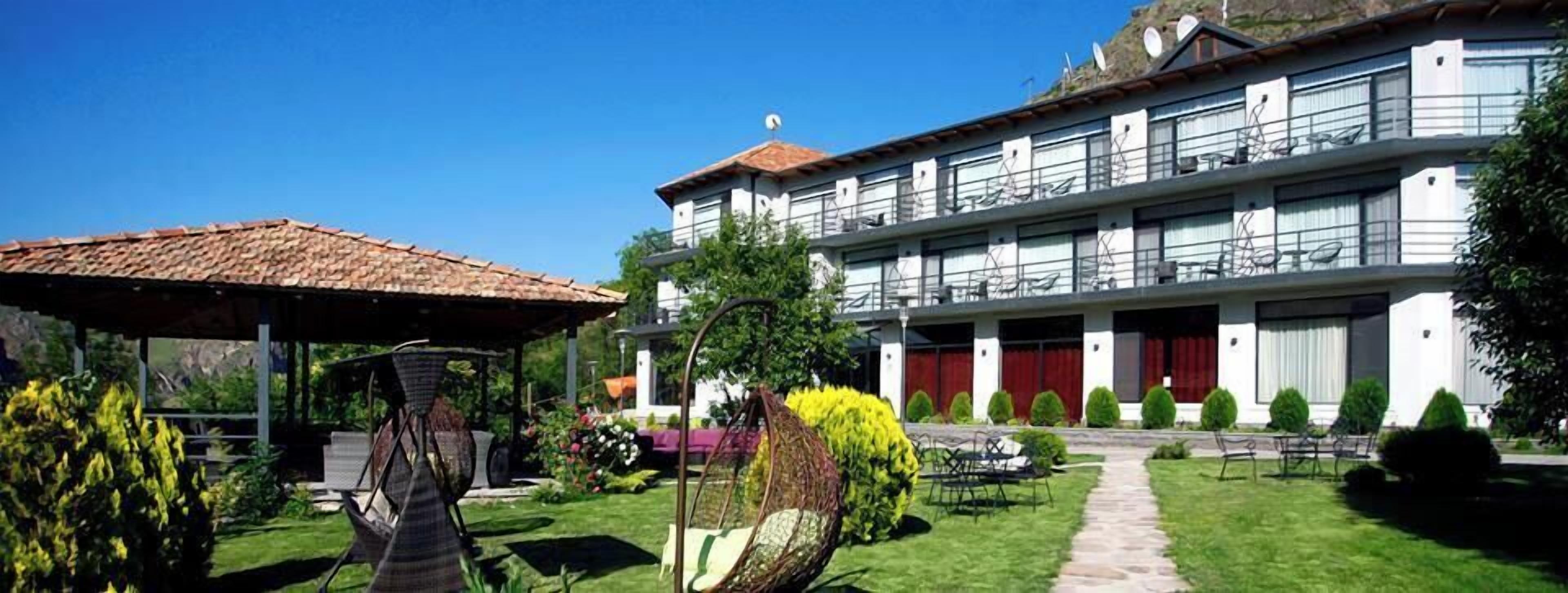 A two-story building with a covered patio area, outdoor seating, and a well-maintained garden.