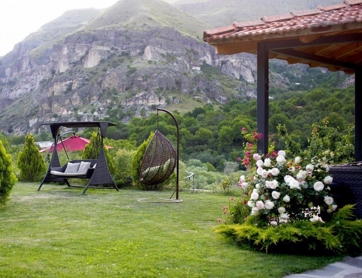 A garden with a swing chair, a hanging chair, and a flower bed.
