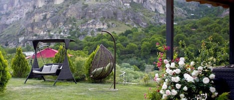 A garden with a swing chair, a hanging chair, and a flower bed.