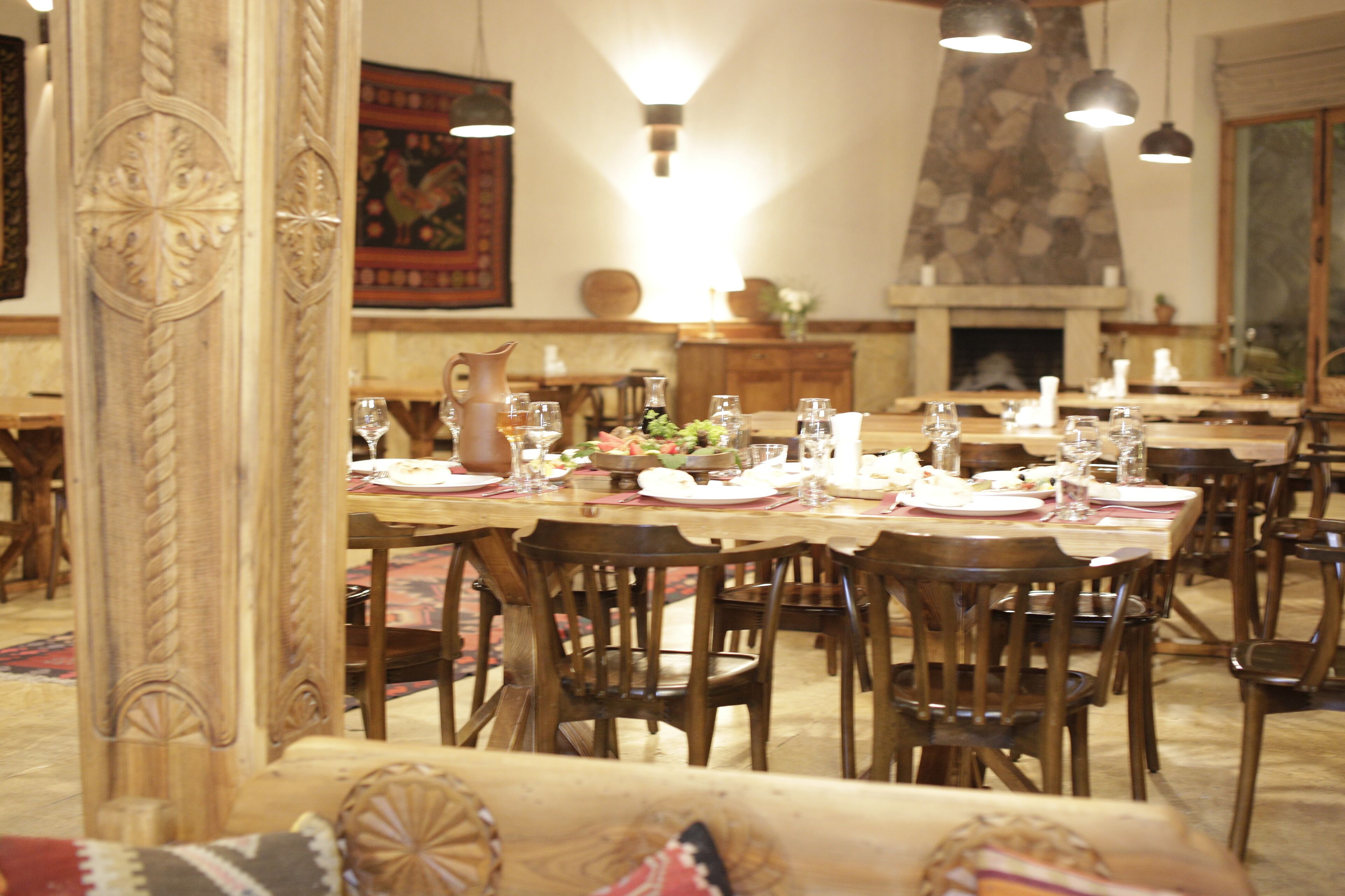 A dining area with wooden tables and chairs, a fireplace, and a decorative wall.