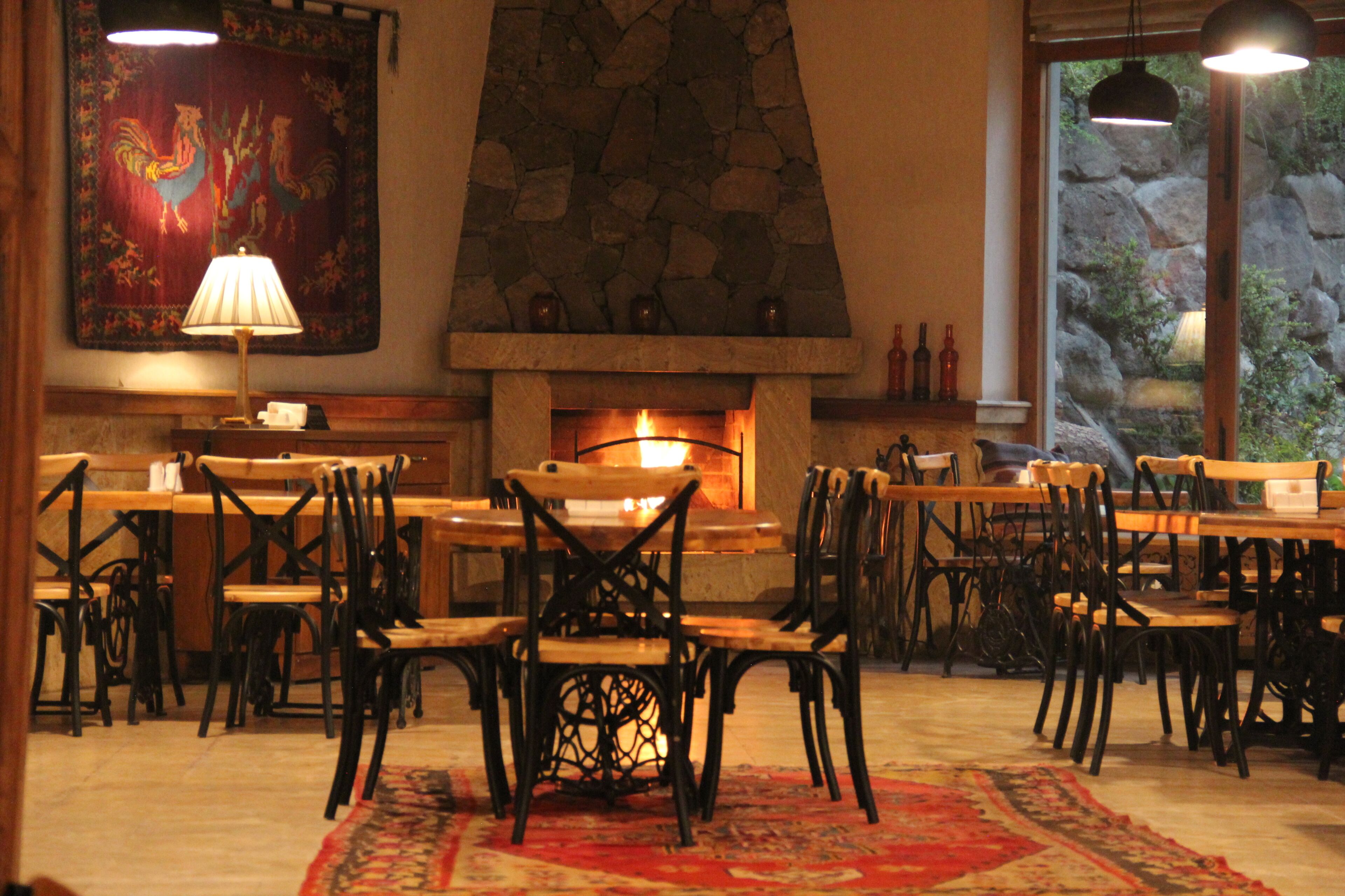 A dining area with a stone fireplace, wooden tables, and chairs.