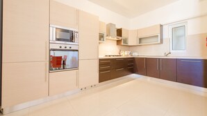 A modern kitchen with a built-in oven, microwave, and stainless steel range hood. - Vacation Rentals (St. Paul's Bay)