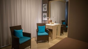 Ein Zimmer mit zwei Korbstühlen mit türkisfarbenen Kissen, einem Holztisch und einem Spiegel.
