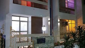 A multi-story building with balconies, a gated entrance, and a stone wall with a plaque. - Maplewood Stay (New Delhi)