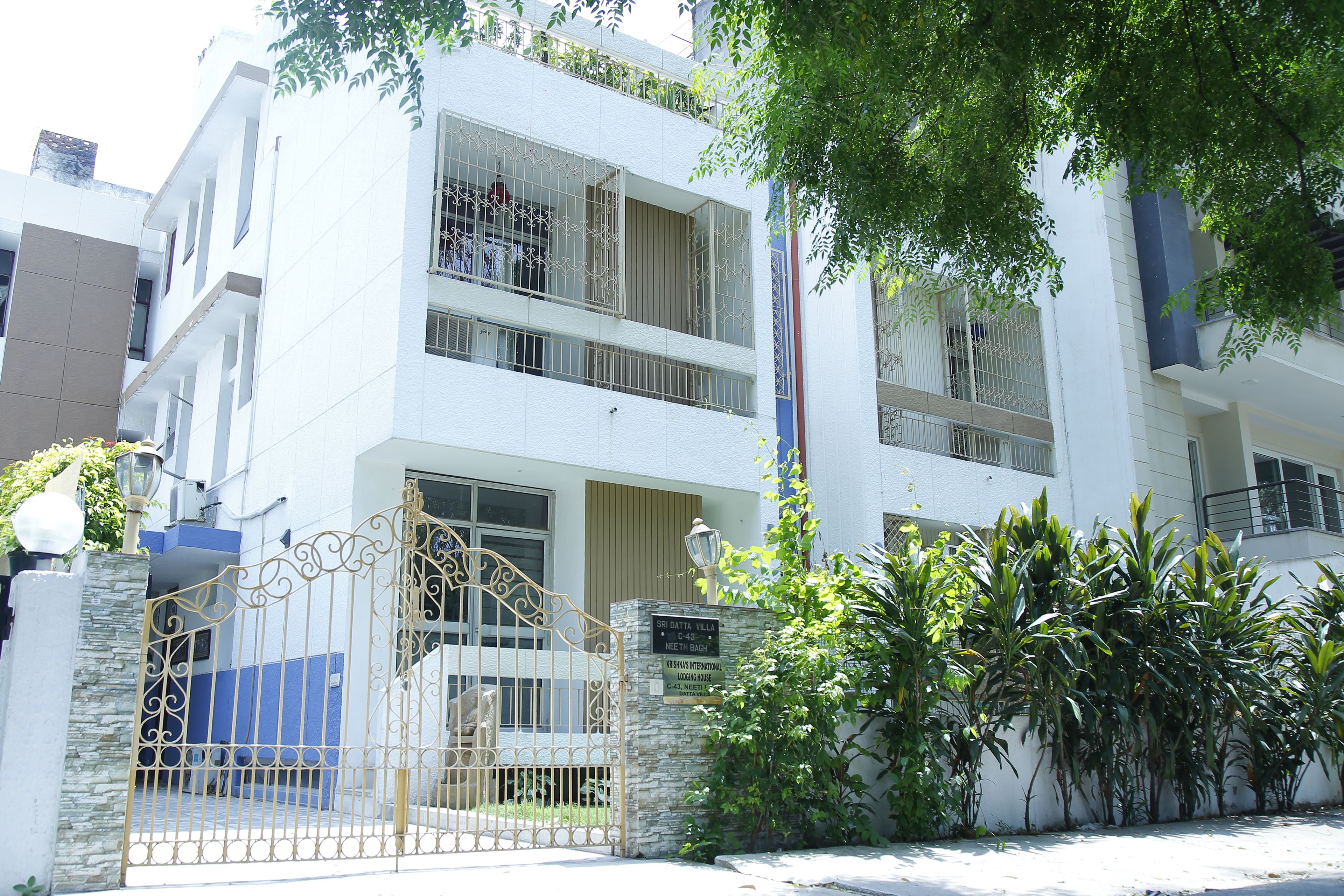 A multi-story building with a gated entrance, balconies, and a sign indicating the building's name and address.
