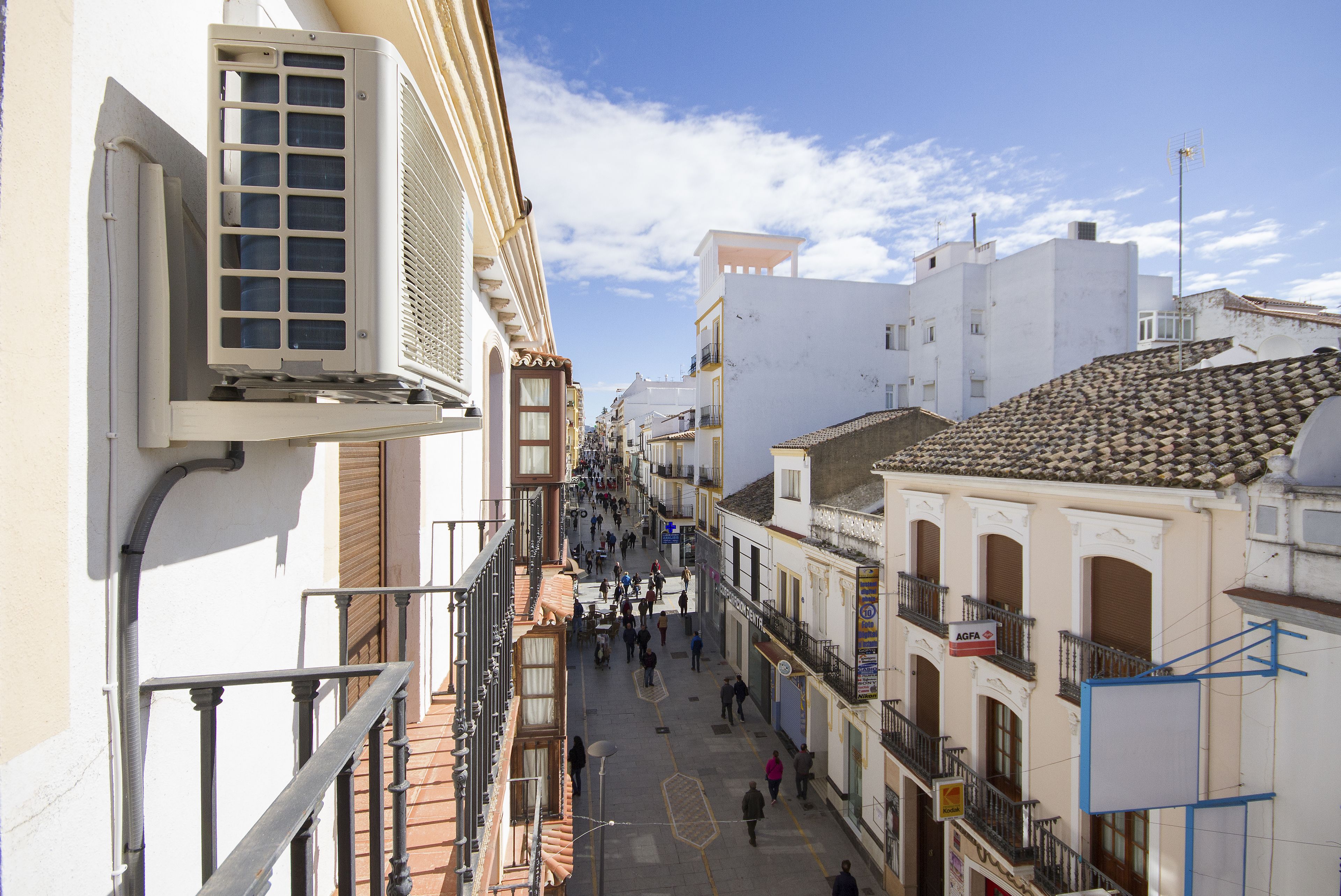 Una calle estrecha flanqueada por edificios, balcones y un cielo despejado.