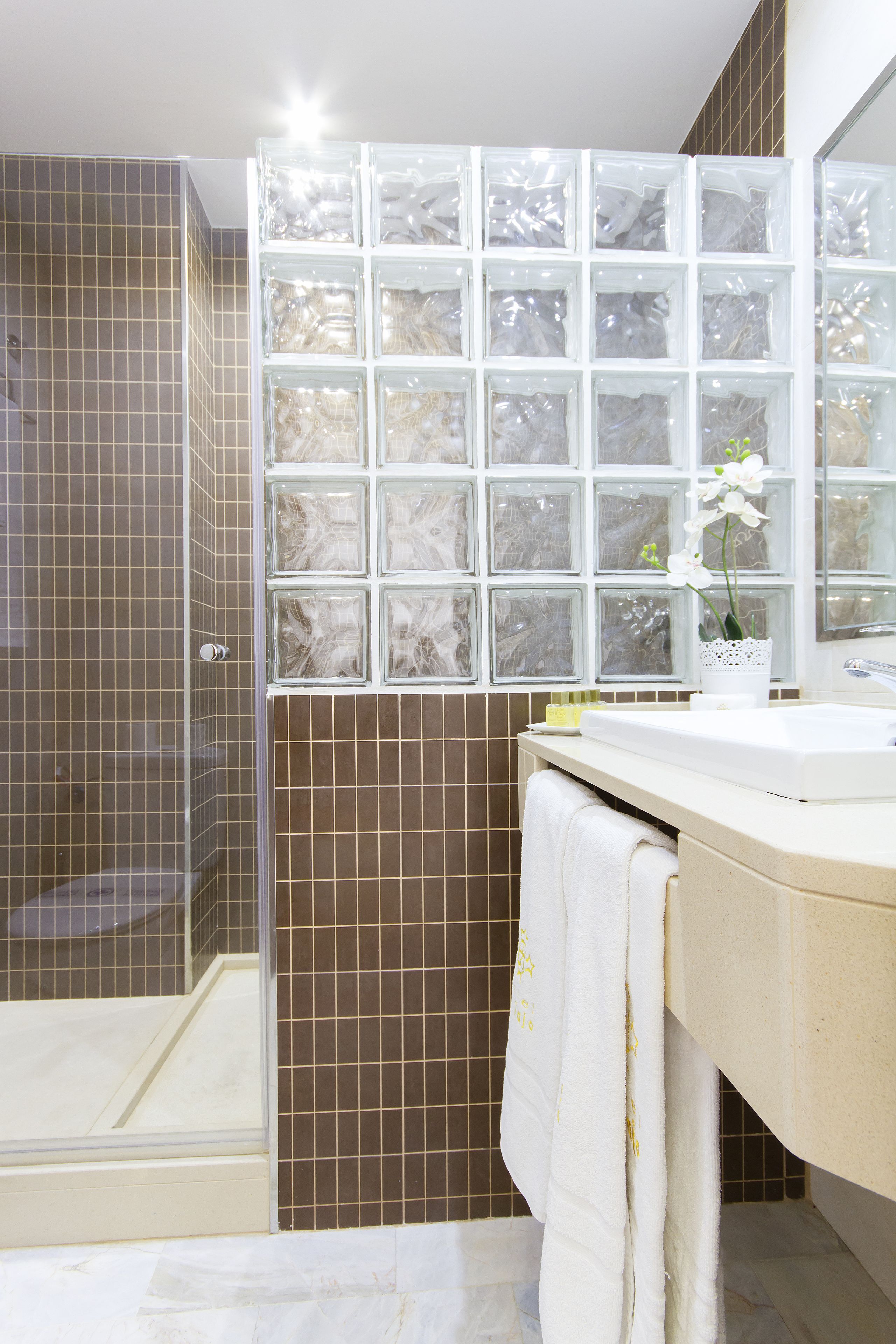 Un baño con ducha, lavamanos y espejo.