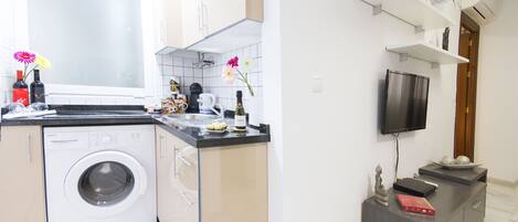 Una cocina moderna con lavadora, televisor de pantalla plana y horno empotrado.