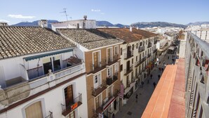 A narrow street with buildings featuring terracotta roofs and balconies. - Apartamentos El Tajo (Ronda)