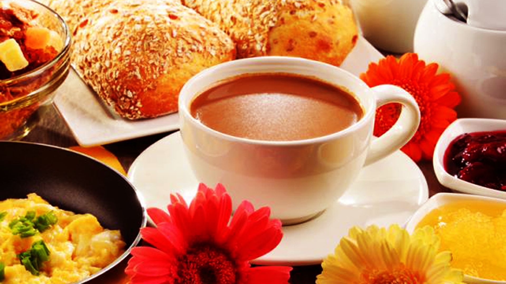Un esmorzar preparat amb una tassa de cafè, pastissos i diferents plats.