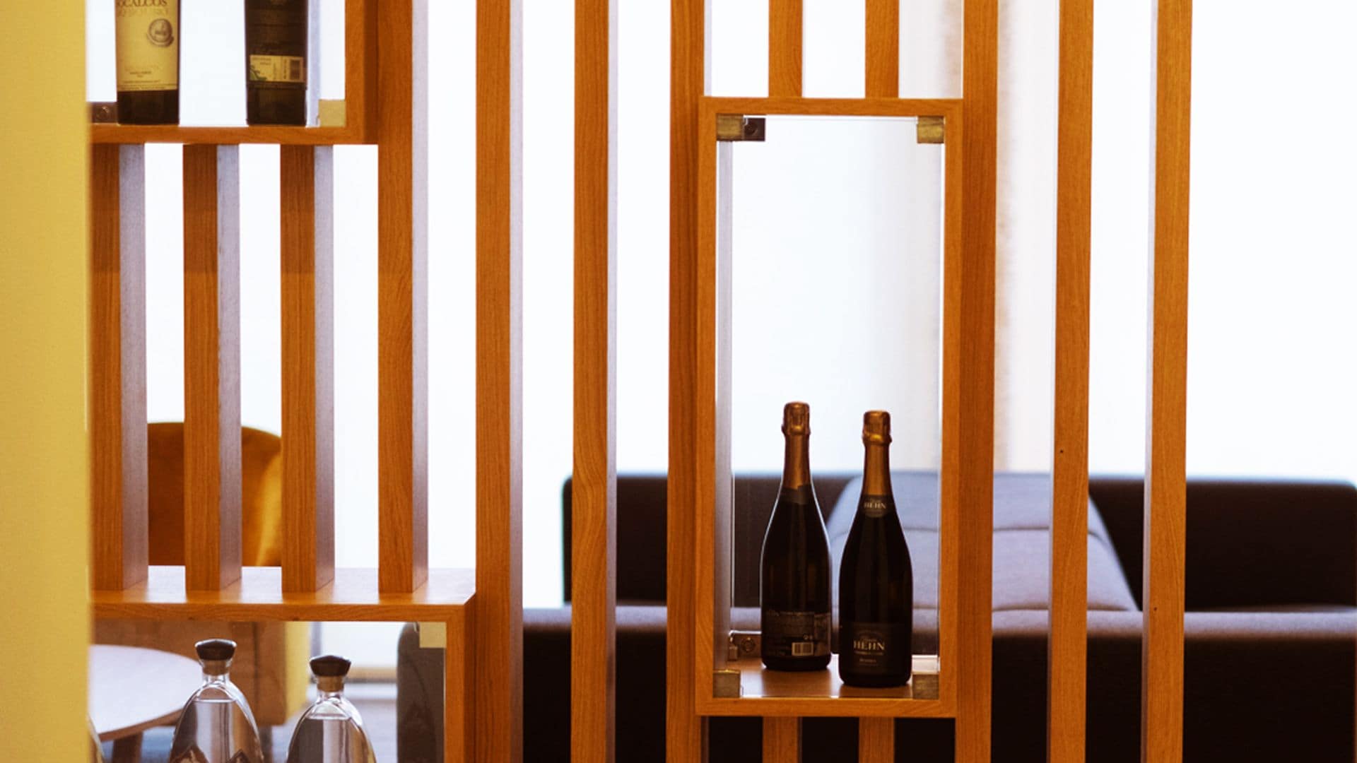 A wooden partition with two bottles of wine on a shelf.
