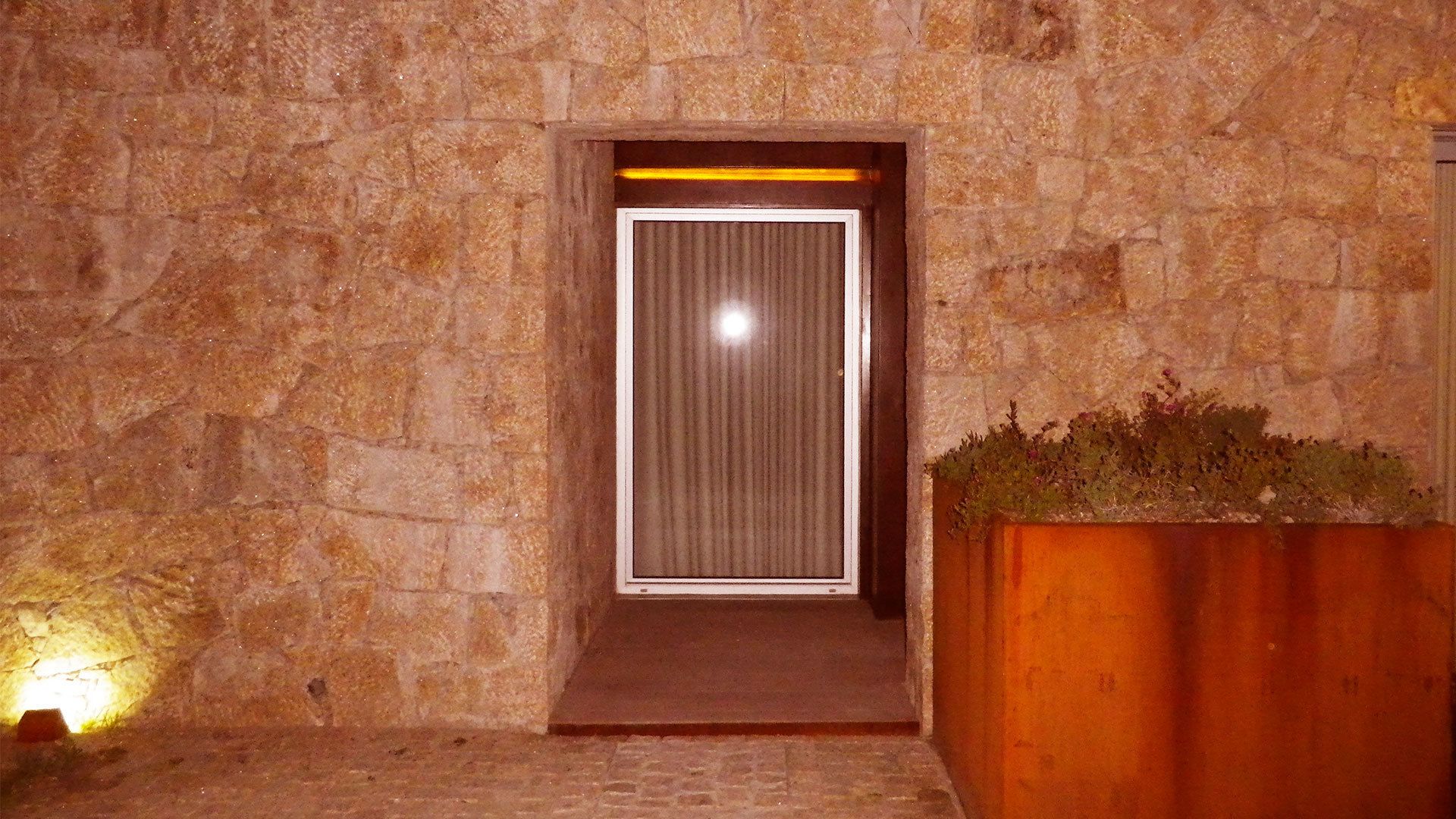 A stone-walled entrance with a door featuring vertical blinds.