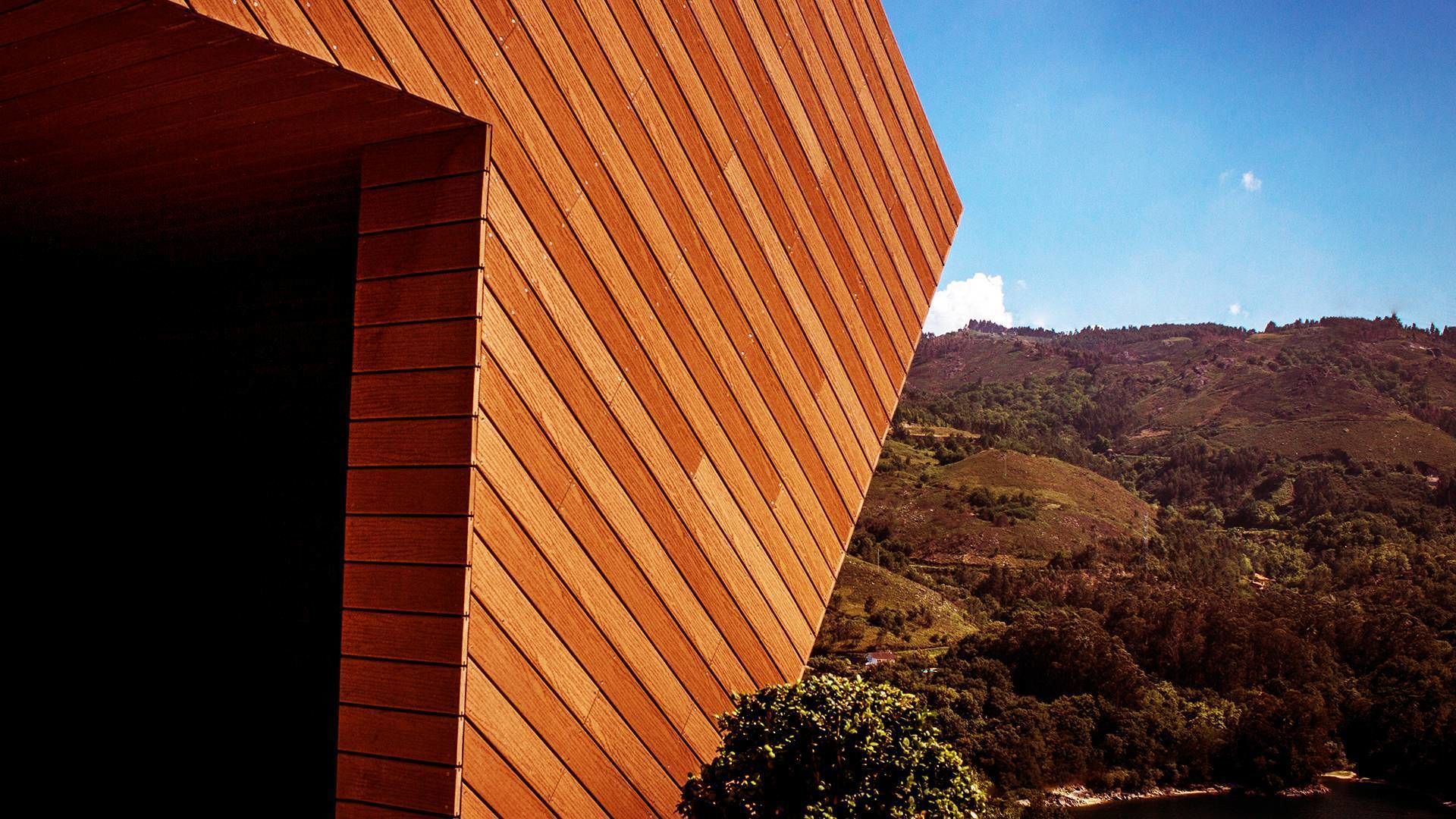 Un edificio moderno con fachada de madera y vistas a un paisaje montañoso.