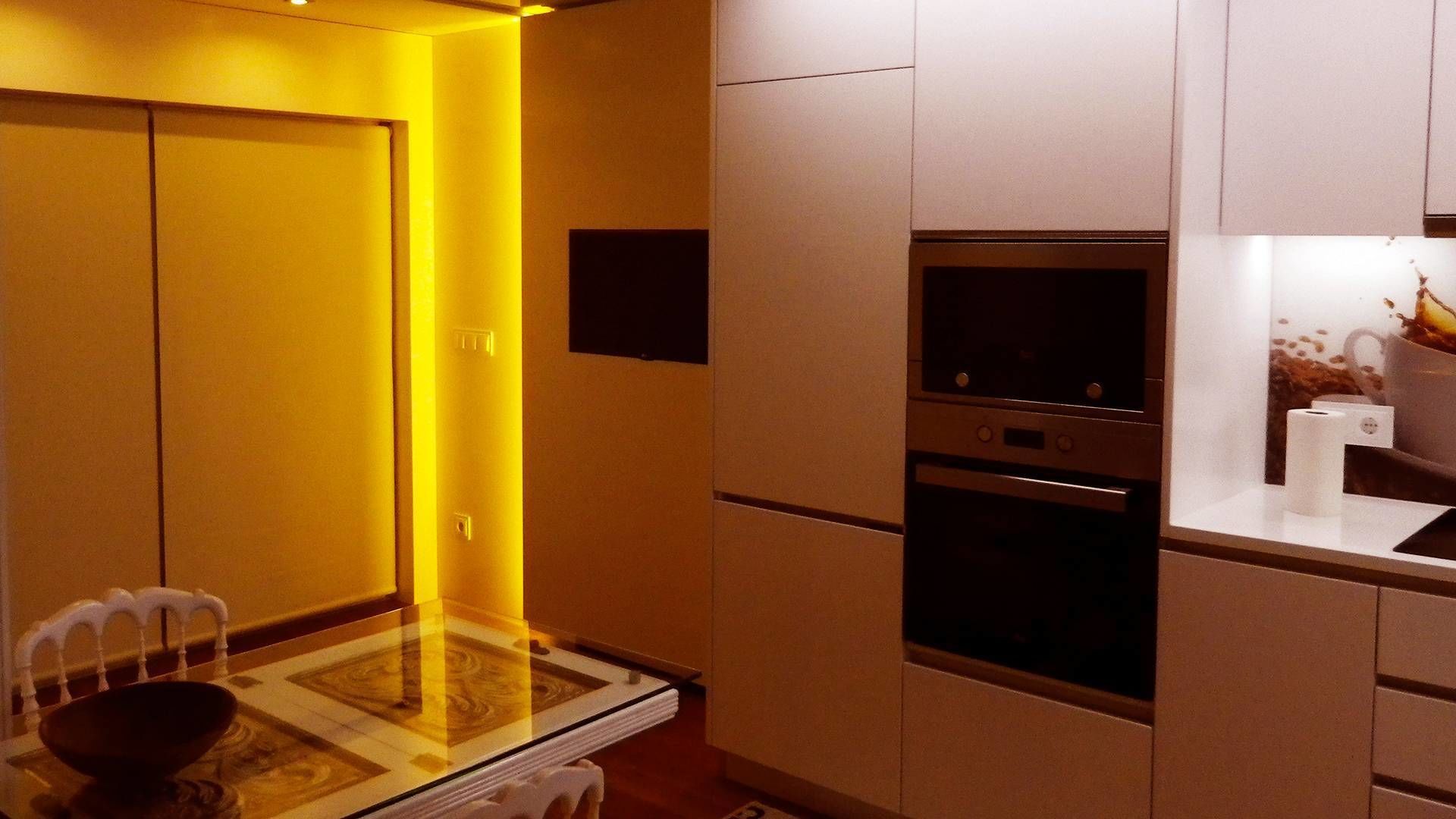 Una cocina moderna con una mesa de vidrio, horno empotrado y microondas.