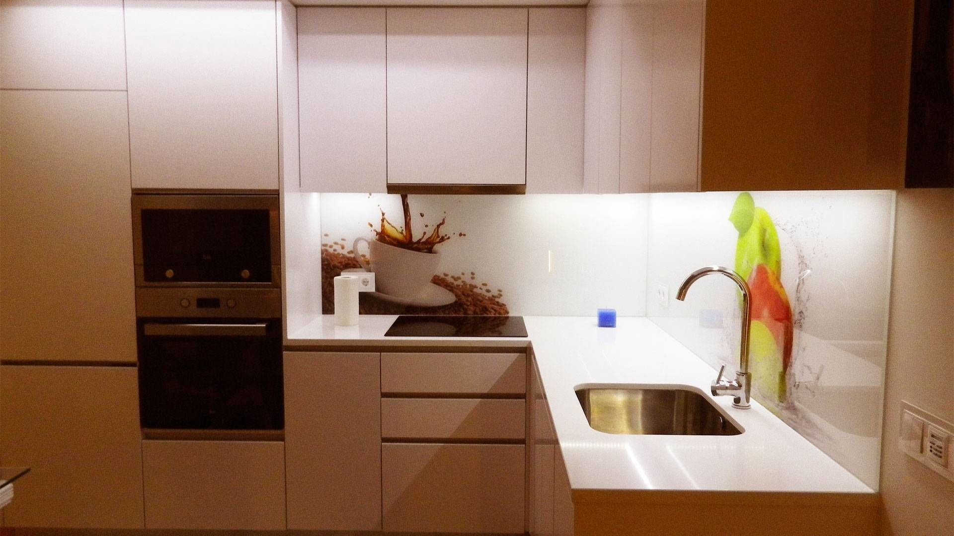 A modern kitchen with a built-in oven, a stainless steel sink, and a decorative splash of coffee on the countertop.