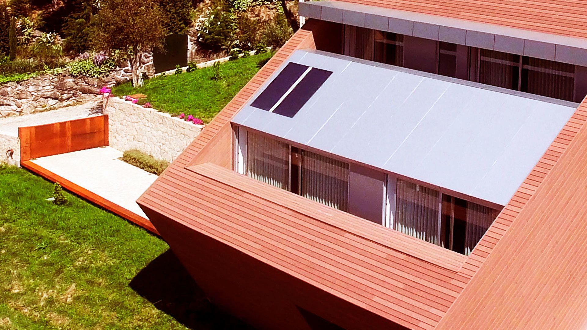 A modern building with a sloped roof, large windows, and a flat roof section.
