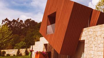 A modern building with a unique angular design, featuring a stone wall and a wooden facade.
