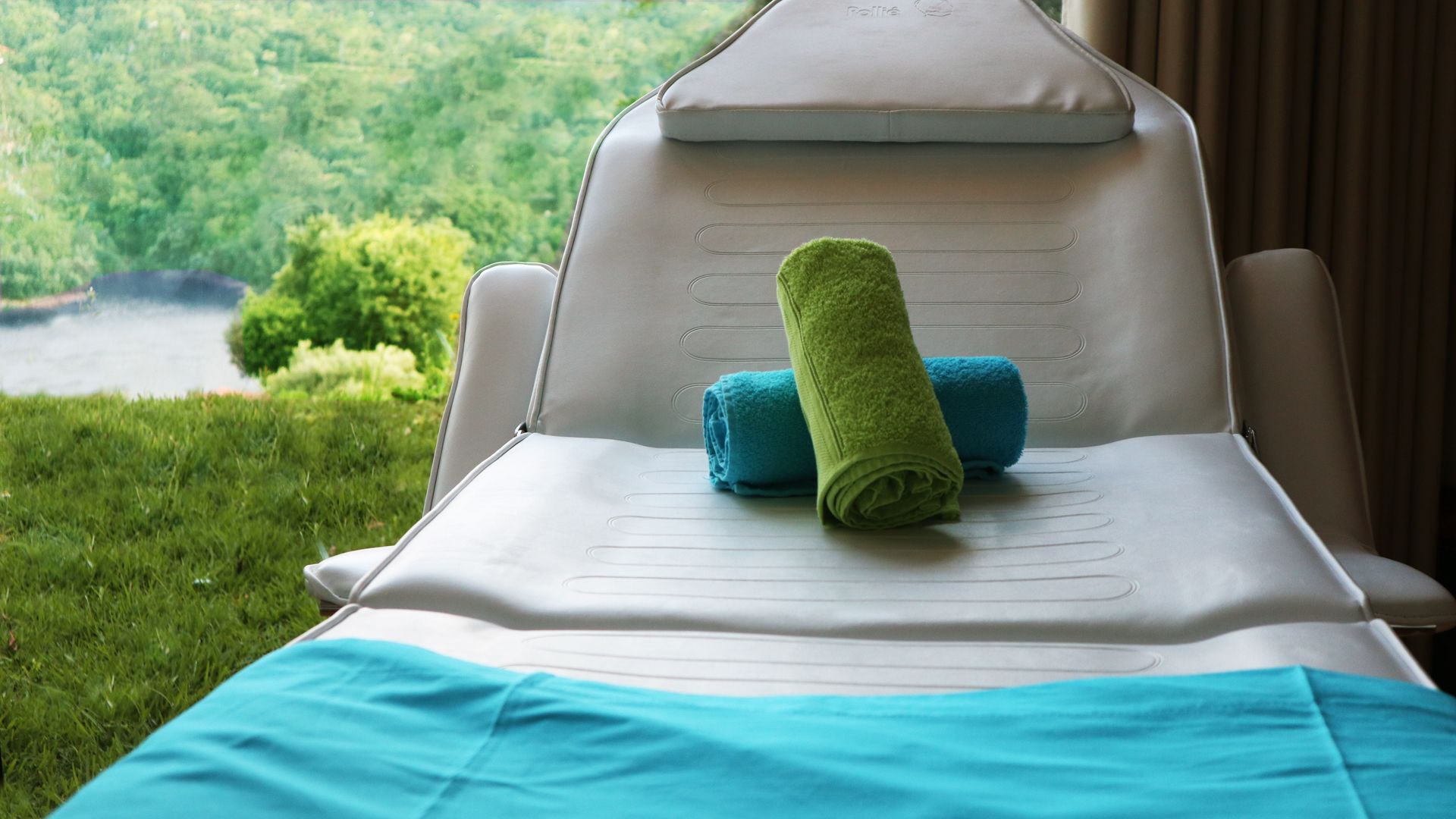 A sun lounger with a view of a lake and greenery.