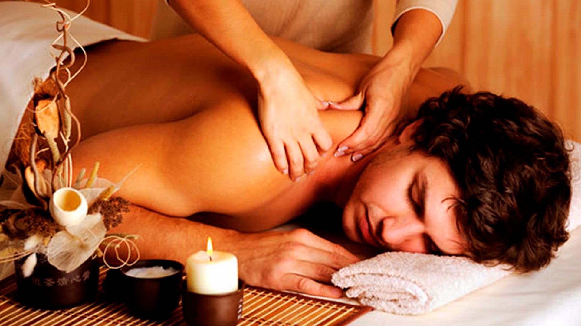 Une personne reçoit un massage, une bougie, un bol et une serviette sont posés sur la table.